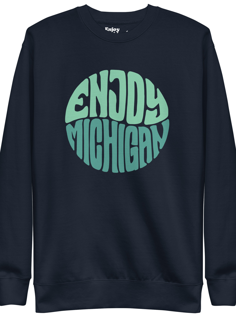 Enjoy Michigan 70's Retro Premium Sweatshirt shown in navy with a throwback 70's Enjoy Michigan circular graphic printed in greens on the front. By Enjoy Michigan.
