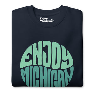 Enjoy Michigan 70's Retro Premium Sweatshirt shown in navy with a throwback 70's Enjoy Michigan circular graphic printed in greens on the front. By Enjoy Michigan.